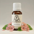 Bottle of Puja Perfumery Geranium essential oil with flowers on a light background