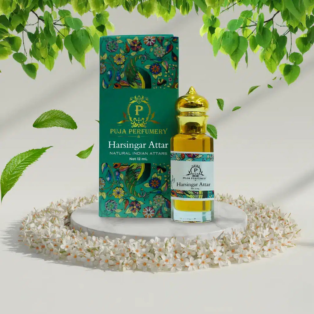 Puja Perfumery Harsingar Attar bottle and packaging with green leaves and flowers in the background