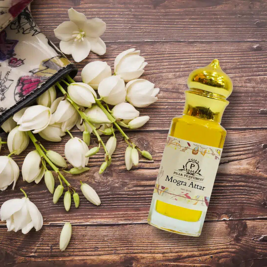 Bottle of Mogra Attar with white flowers on a wooden surface