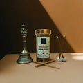 Panchratna Dhoop Sticks container with incense sticks and a bell on a brown surface.