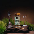 Jar of Rudraksh Dhoop Sticks with a bell and candles on a dark background