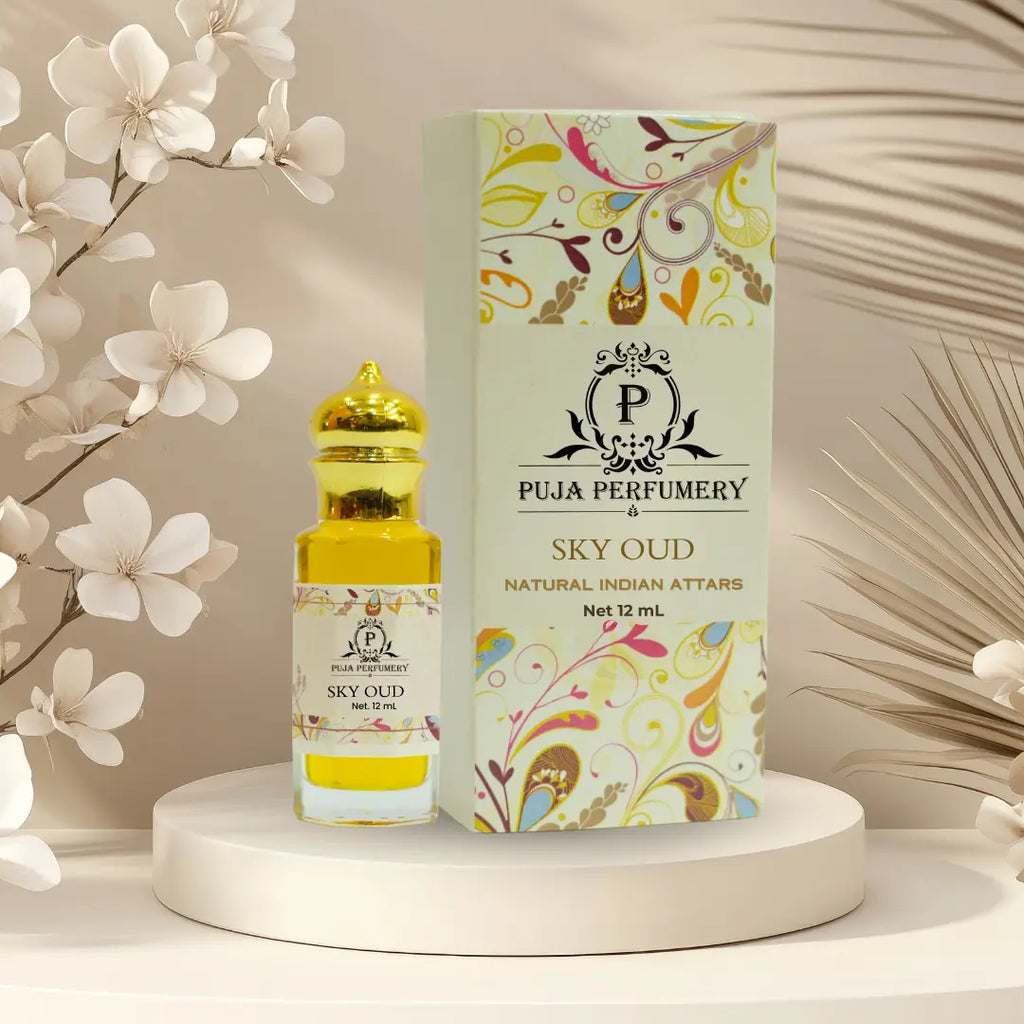 Puja Perfumery Sky Oud perfume bottle and packaging on a decorative stand with flowers in the background